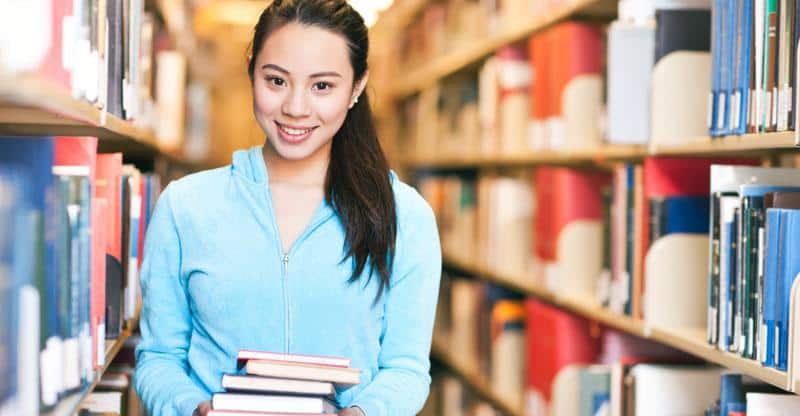 educated Chinese girl holding books in the library