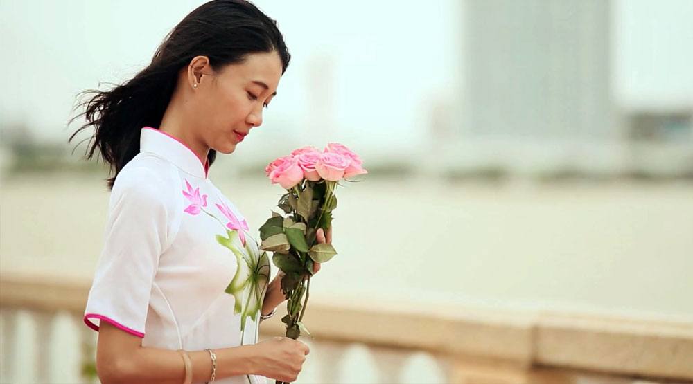 Vietnamese girl wearing a traditional dress holding flowers