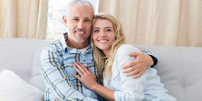 matured man hugging a pretty younger woman