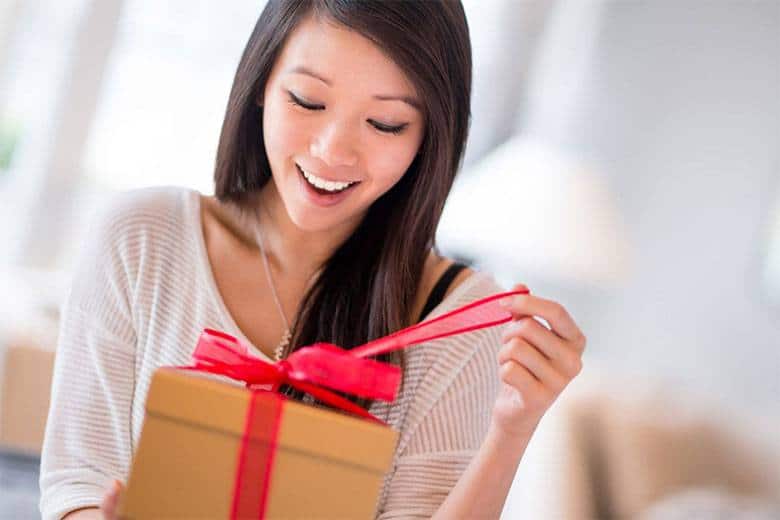 Korean woman looking happy opening a gift