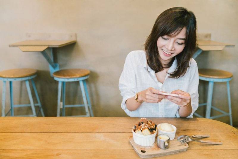 Asian girl taking a photo of food