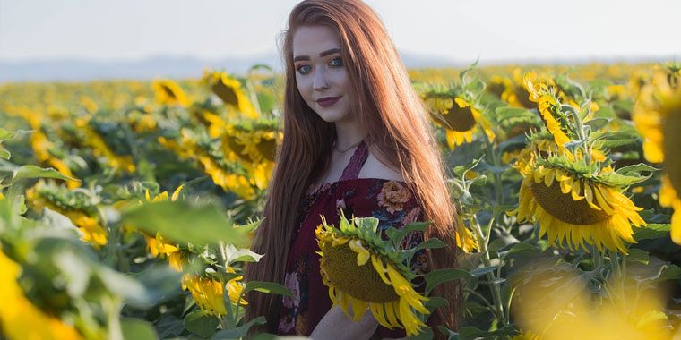 pretty redhead in the middle of the sunflower field