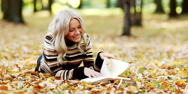 blonde girl reading a book at the park