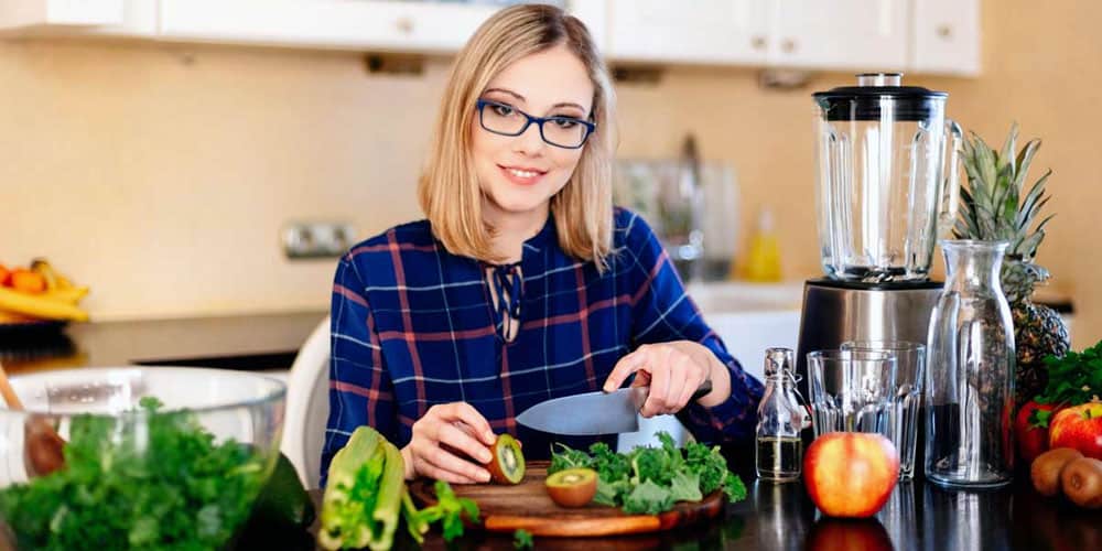 blonde woman cutting fruits in the kitchen