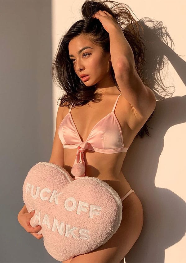 Diana Korkunova in pink two-piece bikini holding a pillow